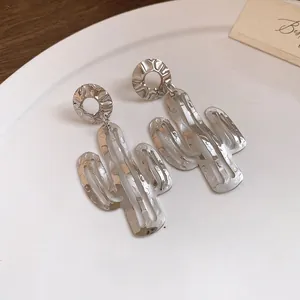 Detailaufnahme von silbernen Kaktus-Ohrhängern mit gehämmerter Metallstruktur