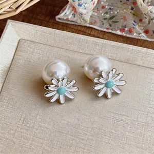 Close-up detail of sweet Korean style daisy flower pearl earrings with blue enamel center