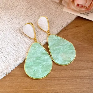 Macro detail of vintage-style mint green resin teardrop shaped dangle earrings