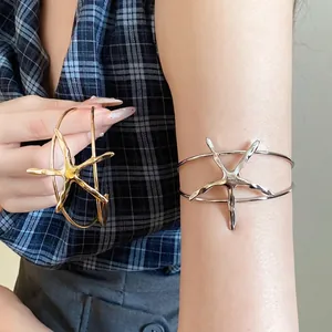 Stylish silver and gold metallic starfish open cuff bracelets displayed on a female model's arm