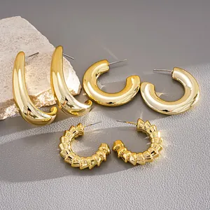 Detailed macro view showing textures of three pairs of gold C-shaped geometric hoop earrings