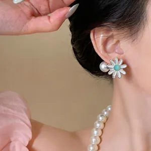 Detail shot of elegant daisy flower stud earrings with large pearl back on female model