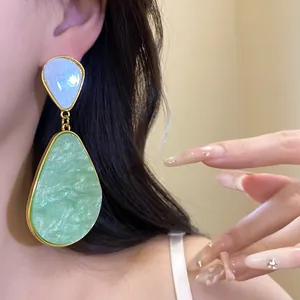 Detailed macro shot of vintage-style green marbled resin teardrop dangle earrings on model