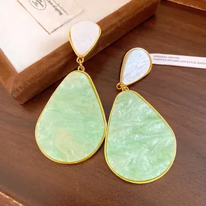 Detailed close-up of vintage resin teardrop earrings in mint green and marble white