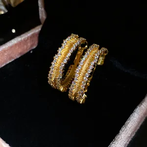 Luxury close-up detail of 18K gold plated hoop earrings with shimmering zircon stones