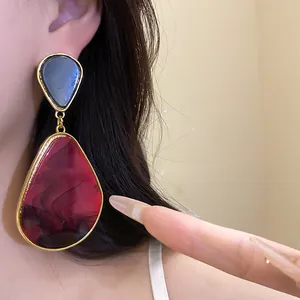 Close-up detail of vintage red and black resin teardrop earrings with gold frames.