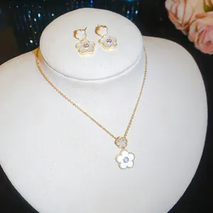 Detailed view of elegant gold-plated jewelry set with white shell flower pendants
