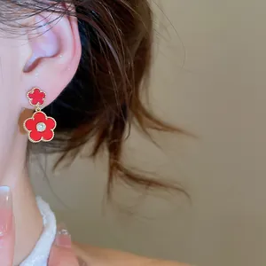 Detailed view of red enamel flower drop earrings with gold plating and zircon stone