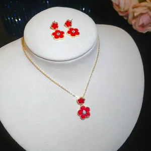 Close-up of gold-plated red zircon flower necklace and earrings set on a white display stand