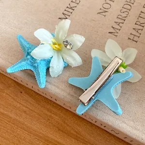 Detailed view of blue starfish hair clip with white flower and crystal