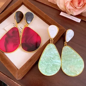 Close-up of vintage resin drop earrings featuring marble texture and gold-toned metal trim