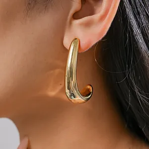 Detailed close-up view of a polished gold C-shaped geometric earring worn on an ear