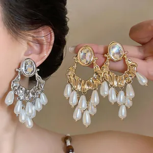 Detailed view of luxury oversized rhinestone earrings featuring elegant white pearl tassels