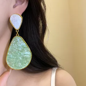 Close-up detail of vintage style green and white resin waterdrop earrings on an Asian model