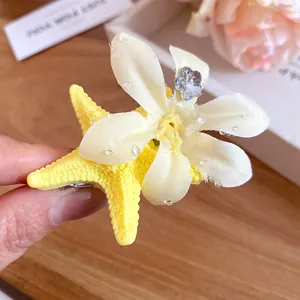 Macro view of yellow starfish hair clip with elegant white flower and blue crystal.