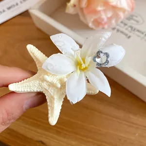 Close-up of starfish and flower hair clip with water drop detail and crystal center
