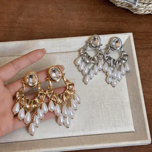 Close-up of ornate earrings featuring oval crystals and elegant teardrop pearl tassels