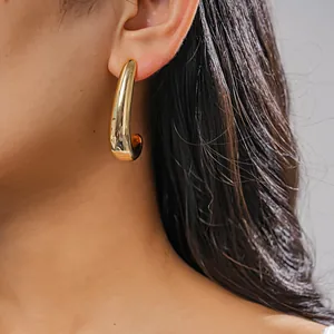 Close-up of a minimalist gold chunky C-shaped hoop earring on a model's ear