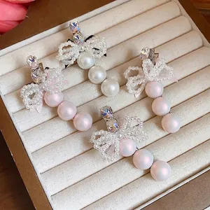 Set of four elegant pearl hair clips with rhinestone bow designs displayed in a luxury jewelry box