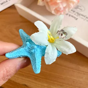 Macro detail view of a blue starfish and white flower hair clip for summer holiday