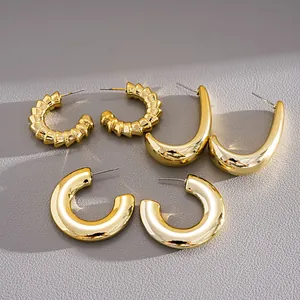 Close-up of three pairs of chunky gold C-shaped hoop earrings with silver steel posts