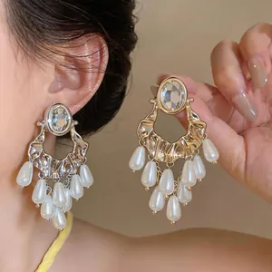 Detail of oversized luxury earrings with pearl tassels and rhinestone oval studs