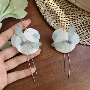 Close-up detail of summer butterfly shell flower hook earrings with elegant long tassels