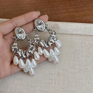 Close-up detail of oversized silver hoop earrings with rhinestones and white pearl tassels