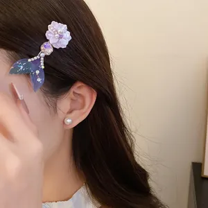 Dettaglio di un fermaglio per capelli in acetato iridescente con fiori e coda di sirena