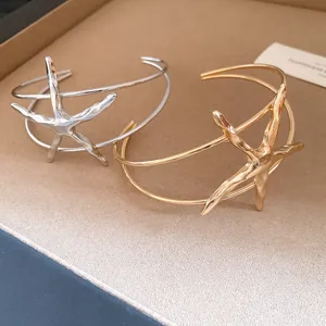 Detailed view of gold and silver textured metal starfish open cuff bracelets