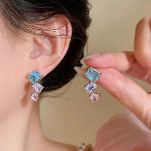 Detailaufnahme von Silbernadel-Ohrringen mit blauen, lila und rosa Zirkonia-Steinen
