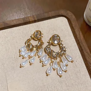 Detailed view of ornate gold earrings with oval crystals and white pearl tassels