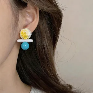 Elegante gelbe Blumenohrringe mit blauer Perle an Model, schicker Urlaubsstil Look