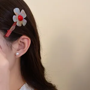Vista dettagliata di un vivace fermaglio per capelli a fiore in acetato sui capelli di modella.