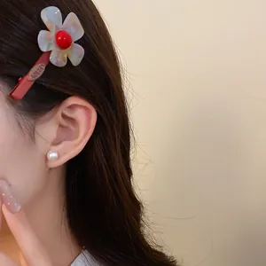 Primo piano della molletta per capelli a fiore in acetato colorato portata sui capelli.