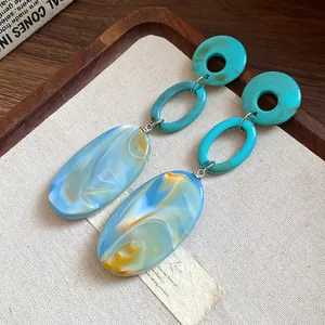 Detailansicht von marmorierten blau-gelben Harz-Ohrring-Anhängern auf einem Tablett.