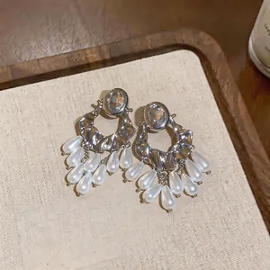 Detailed view of silver statement earrings with crystal studs and teardrop pearl fringes.