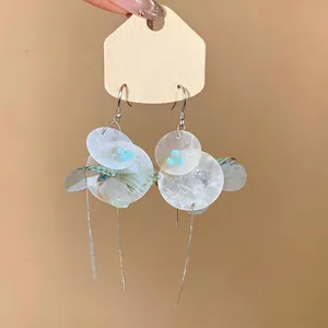 Detail view of butterfly shell flower tassel earrings with chiffon wings and silver hooks.