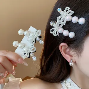 Detailed view of an elegant pearl and rhinestone bow hair clip on dark hair