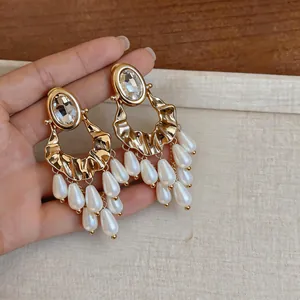 Close-up of luxury gold statement earrings with crystal studs and pearl tassels for women