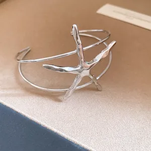 Close-up of a silver starfish open cuff bracelet with detailed metallic texture