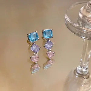 Nahaufnahme von französischen Ohrringen mit blauen, lila und rosa Herz-Zirkonia-Anhängern.