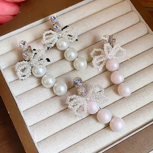 Elegant French style pearl hair clips featuring a rhinestone bow on a jewelry tray
