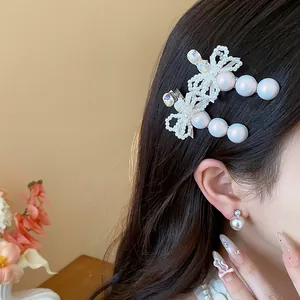 Close-up of an elegant pearl bow hair clip with rhinestones worn on black wavy hair