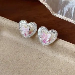 Dettaglio di orecchini a cuore in argento con motivo a farfalla e bordi incisi