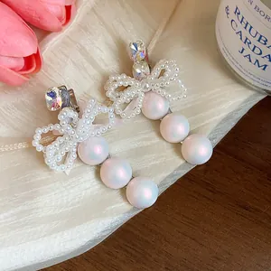 Close-up of elegant rhinestone bow and pearl hair clips on a decorative tray.