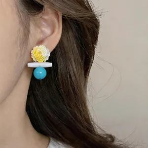 Elegante gelbe Blumen-Ohrstecker mit türkisfarbenen Perlen an einem asiatischen Model