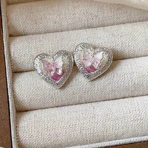 Primo piano di orecchini a forma di cuore con un intricato design a farfalla
