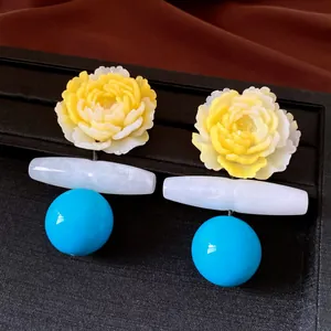 Detailansicht gelber Pfingstrosen-Ohrringe mit weißem Stab und blauer Kugel.