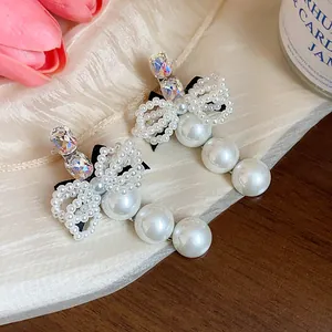 Detailed macro shot of elegant French style pearl and rhinestone bow hair clips on silk fabric